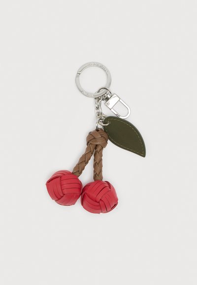 Μπρελόκ με ασημένιο δαχτυλίδι, δύο πλεγμένους καφέ βλαστούς με κόκκινες υφαντές μπάλες και ένα μικρό σκοτεινό πράσινο δερμάτινο φύλλο προσαρτημένο.