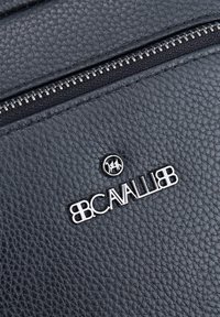 Zaino in pelle nera con superficie a granuli e zipper argento con dettagli del logo. Presenta una superficie testurizzata e accenti hardware eleganti.