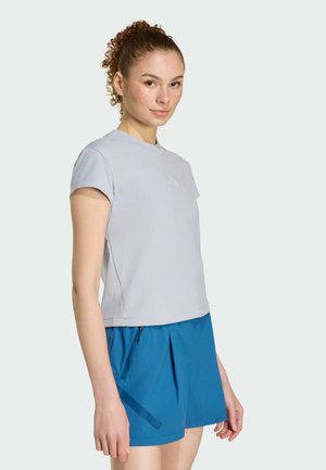 Light gray short-sleeve athletic top with a round neckline, worn with blue shorts featuring a side zipper pocket and pleated design.
