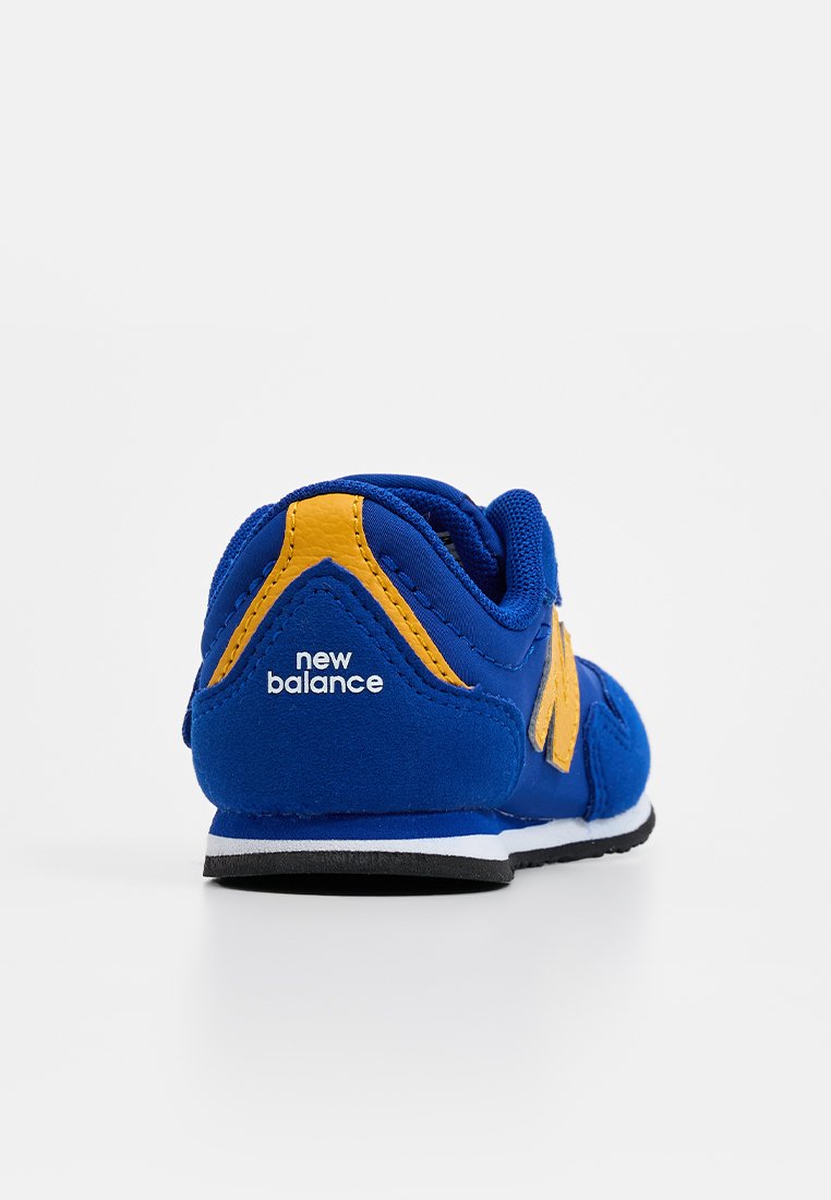 Baskets en suède bleu avec des accents jaunes, dotées d'un logo au dos, d'un col rembourré et d'une semelle en caoutchouc noir. Forme arrondie et finition texturée.