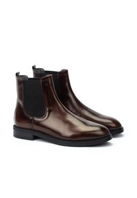 Botas Chelsea de cuero marrón con paneles laterales elásticos y tiradores. Textura suave, punta redondeada y suela de goma plana para mayor estabilidad.