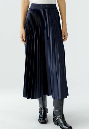 Jupe midi plissée marine avec une taille ajustée. Fabriquée à partir d'un tissu lisse et brillant, avec de profonds plis qui créent de la texture et du mouvement.
