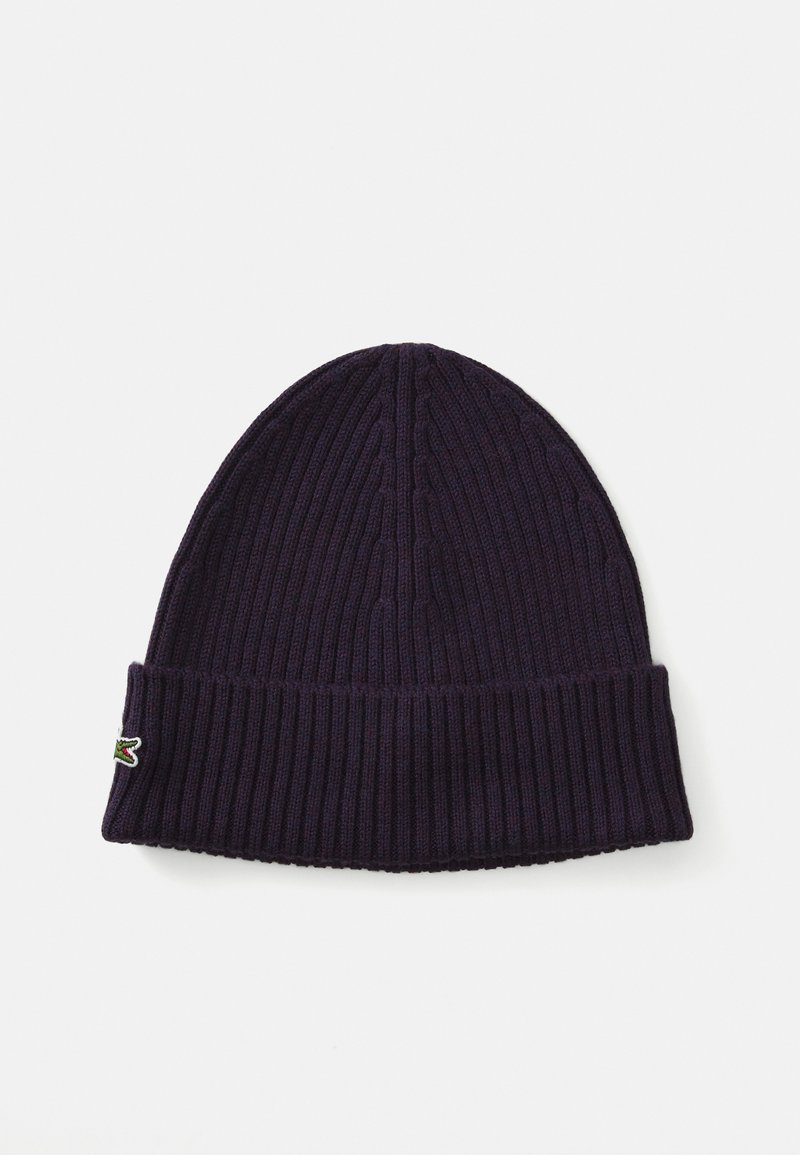 Béret en tricot violet avec une texture côtelée et un revers. Présente un petit logo brodé sur le côté. Matériau doux idéal pour la chaleur.