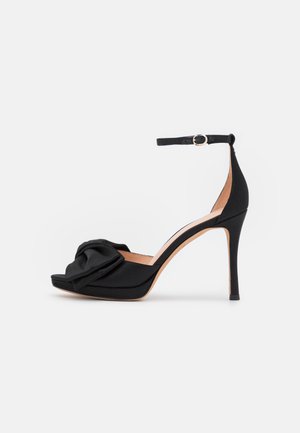 Mustad kõrge kontsaga sandaal satenist ülaosaga, millel on ees sõlme detail, pahkluu rihm ja stilettokonts.