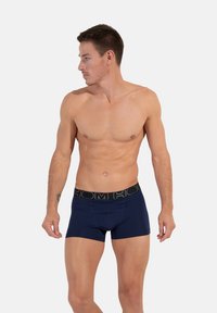 Mörkblå boxershorts med svart elastiskt midjeband som har "HOM"-logotypen. Mjuk material, åtsittande design och längd till mitten av låret.