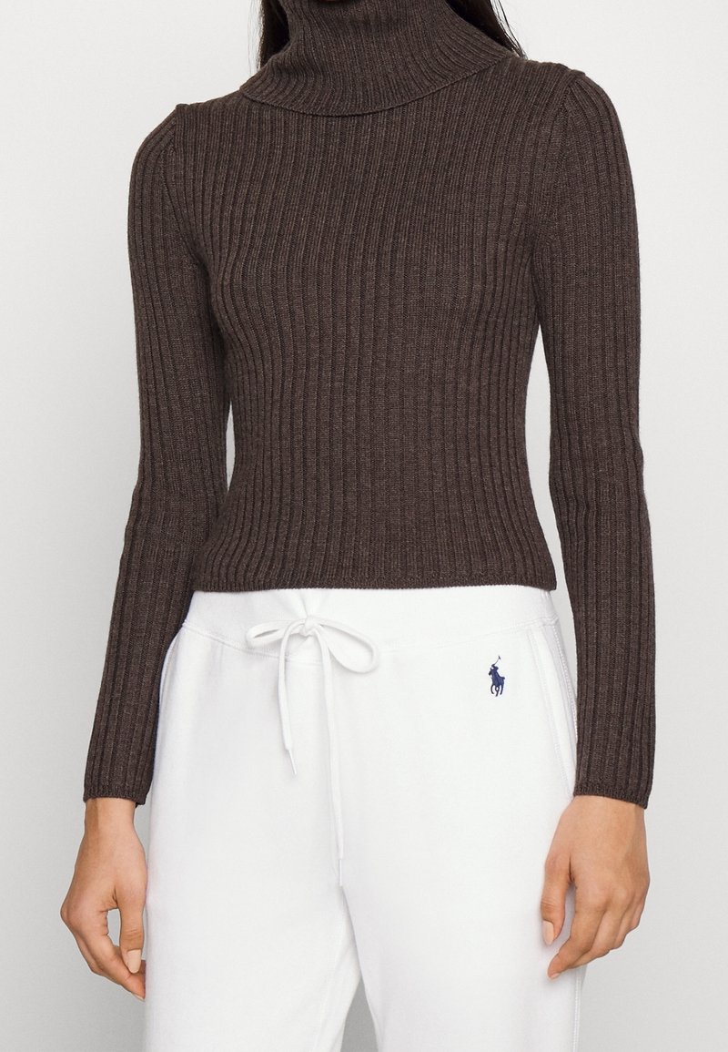 Brun, ribbad polotröja med långa ärmar, åtsittande design och mjuk textur, parat med vita sweatpants med en logotyp.