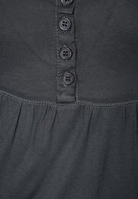 Svart bomullstygklänning med knappstängning fram med fem mörka knappar och en samlad nederdel. Mjuk textur och en enkel design.