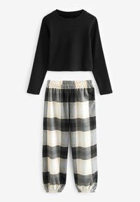 Sort langærmet cropped top med rund hals, parret med grå og sort ternede bukser med elastisk talje og manchetter ved anklerne.