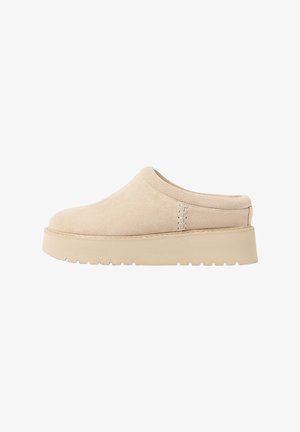 Beige Wildleder Slipper mit gerundeter Zehenpartie und dicker, strukturierter Plateausohle. Verfügt über minimale Nähte und ein sanftes Design.