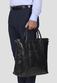 Zwart leren tote bag met twee handvatten aan de bovenkant, met een gladde textuur, rechthoekige vorm en subtiele stiksels.