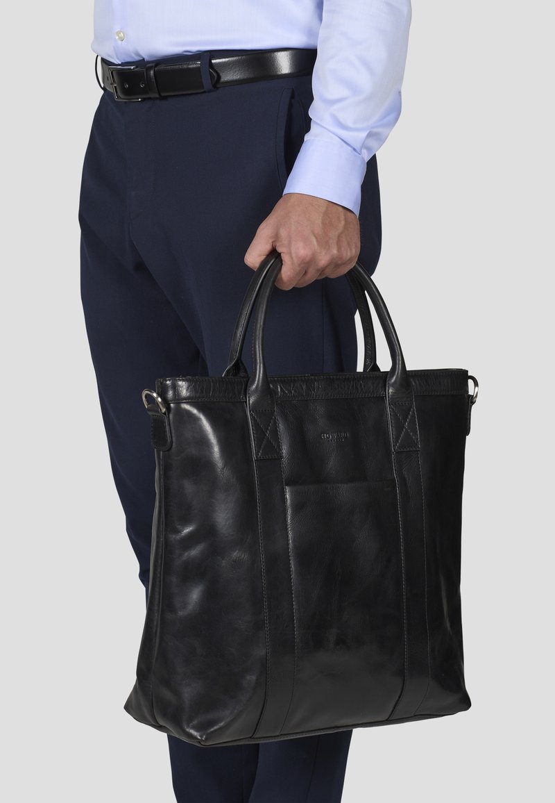 Zwart leren tote bag met twee handvatten aan de bovenkant, met een gladde textuur, rechthoekige vorm en subtiele stiksels.