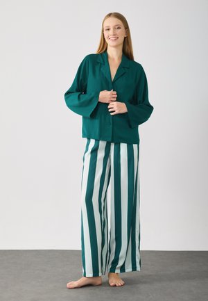 Haut teal à boutons avec des manches larges, associé à un pantalon large à rayures teal et blanc. Tissu lisse, design minimal, texture douce.