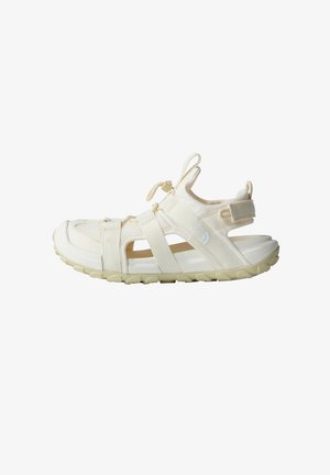 Light beige outdoor sandal made of synthetic material, featuring a closed toe, wide adjustable straps, and textured rubber sole with grip.