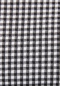 Svartvit rutigt tyg med en vävd struktur, med växlande rutor i ett klassiskt gingham-mönster.