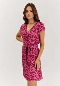 Ružové leopardie vzorované šaty s výstrihom do v a krátkymi rukávmi. Majú opasok v páse a splývavý strih. Hladká textúra látky.