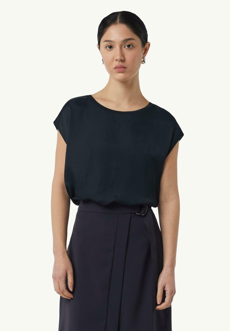 Granatowa jedwabna bluzka z okrągłym dekoltem i krótkimi rękawami, połączona z ciemną, plisowaną spódnicą. Gładka tekstura i luźny krój.