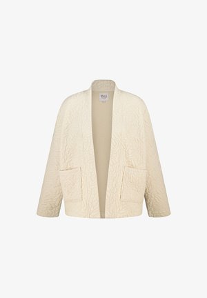 Gequilte crèmekleurige kleding met een ontspannen pasvorm, voorzien van een V-hals, open voorkant en twee zijzakken. Geweven patroon overal.