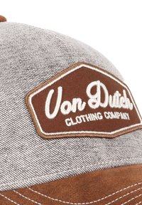 Casquette en denim gris avec une patch brodé marron portant "Von Dutch" et "Clothing Company". La casquette a une forme structurée et des détails de couture.