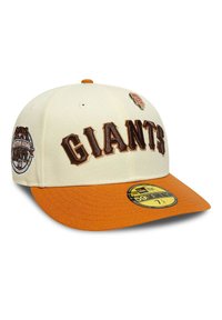 Gorra de béisbol crema con visera naranja. Presenta letras en relieve "GIANTS", parches laterales y un logotipo circular en el panel frontal.