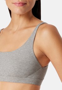 Harmaa ribattu bralette, jossa on leveä vyötärö, ohuet hihnat ja saumatön muotoilu pehmeällä pinnalla. Väri on sileä, vaalea harmaa.