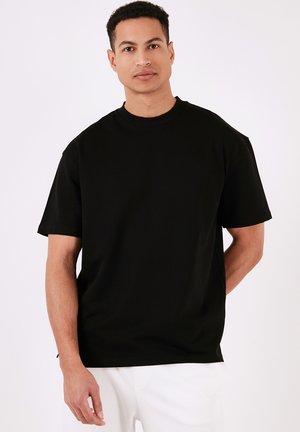 Sort kortærmet t-shirt i en afslappet pasform, lavet af blødt bomuld. Rund halsudskæring med et enkelt, rent design. Ingen synlige mønstre eller detaljer.