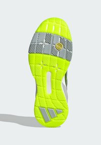 Shoe sole in gray and neon yellow, featuring textured patterns, a circular yellow accent, and a geometric logo detail.