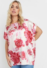 Blommig satin-topp med stora rosor i rött och rosa på en ljus bakgrund, korta ärmar och en avslappnad passform.