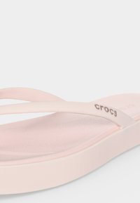 Ανοιχτό ροζ σαγιονάρα Crocs με απλή λουρίδα που φέρει το λογότυπο Crocs σε μονόχρωμο φόντο.