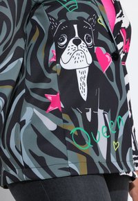 Giacca corta e fantasia caratterizzata da un design di Boston Terrier in bianco e nero, cuori e stelle. Realizzata in tessuto liscio con uno sfondo colorato e astratto.