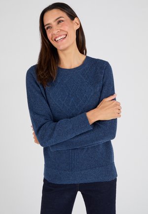 Pull en tricot bleu avec un motif de diamants texturé, col rond et manches longues, assorti à un pantalon en denim foncé.