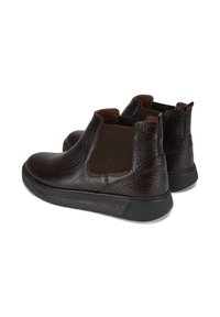 Une paire de bottes Chelsea en cuir marron foncé avec des semelles noires et des panneaux latéraux en élastique, présentée sur un fond blanc.