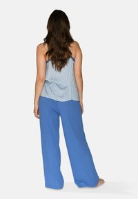 Blue patterned camisole with thin straps paired with wide-leg blue pants. Lightweight fabric, relaxed fit, and smooth texture.