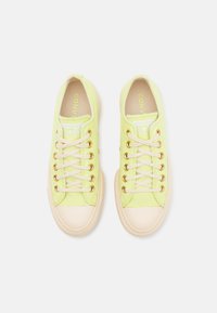 Hellgrüne Leinensneaker mit goldenen Ösen, langen Schnürsenkeln und beigen Gummisohlen. Auf der Zunge steht "CONVERSE ALL STAR."