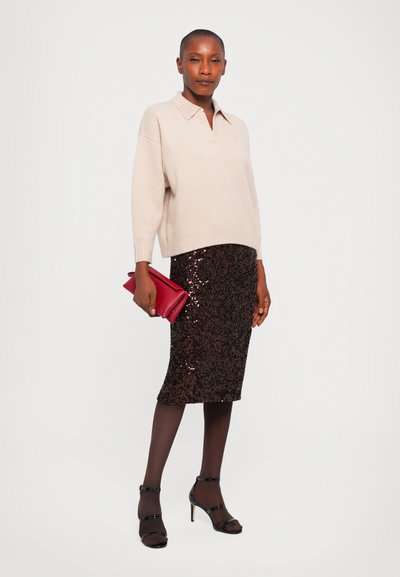 Beige oversized sweater with polo collar, paired with a brown sequin pencil skirt. Model holds a red clutch, wearing black heels and tights.