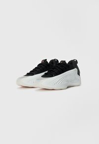 Sorte og hvide sportsko med en struktureret overdækning, bøjet design, mesh-detaljer og en gummisål med grebsmønstre.