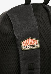 Czarny plecak z tkaniny z teksturowanym siatkowym plecakiem, tkanym haftem z logo "Superdry Machined" oraz regulowanymi ramiączkami.