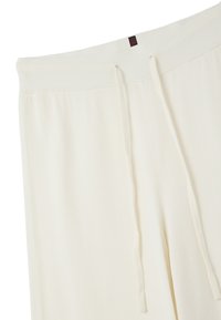Joggers de couleur crème avec une ceinture côtelée, dotés d'un cordon de serrage et d'une texture lisse et douce. Le design est simple et fonctionnel.