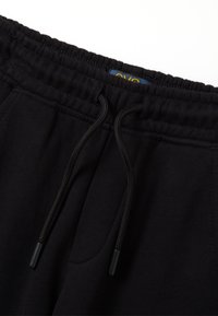 Zwarte joggingbroek met een elastische tailleband, koordjes met plastic uiteinden en zijzakken. Gemaakt van zacht katoenmateriaal.