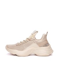 Beige athletic shoe with a textured mesh upper, elastic laces, padded collar, and a decorative metallic accent on the side.