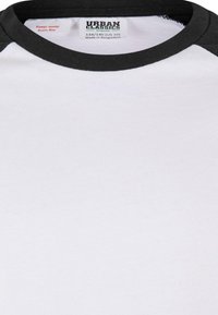Fekete raglán ujjú, rövidujjú póló fehér testtel, környakú kivágással és "URBAN CLASSICS" felirattal birkózó címkével.