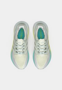 Chaussures de sport blanches avec une tige en mesh, présentant des accents bleu clair, des lacets gris et une semelle dégradée jaune. « ULTRABOOST » imprimé en turquoise.