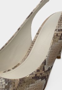 Γυναικείο παπούτσι με ψηλό τακούνι σε σχέδιο φίδι, με χρωματικό συνδυασμό μπεζ και καφέ, ομαλή υφή και καμπυλωτό δισδιάστατο σχέδιο.