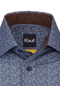 Camicia azzurra a motivo floreale con colletto interno marrone e vestibilità standard. Presenta una chiusura con bottoni e un'etichetta logo sulla nuca.