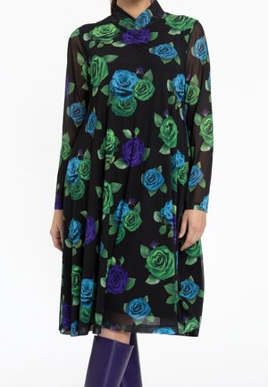 Schwarzes transparentes Langarmkleid mit grünem, blauem und lila Rosenmuster, kombiniert mit kniehohen lila Stiefeln.
