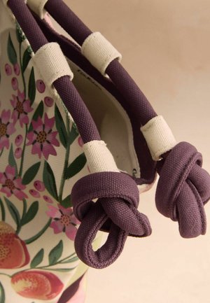 Stofftasche mit violetten, geknoteten Stoffgriffen und Floralmuster mit rosa Blumen und grünen Blättern.