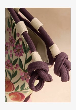 Stofftasche mit violetten, geknoteten Stoffgriffen und Floralmuster mit rosa Blumen und grünen Blättern.