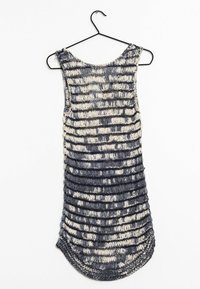 Débardeur en maille bleu marine et crème avec un motif rayé texturé. Ourlet arrondi, design sans manches et côtés ouverts. Suspendu à un crochet en métal noir.