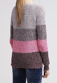 Strickpullover in verschiedenen Farbtönen: Weiß, Grau, Dunkelbraun und Pink. Hat eine lockere Passform, strukturierten Stoff und lange Ärmel.