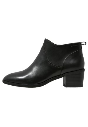 Schwarzer Leder-Stiefelette mit niedrigem Blockabsatz, spitzer Zehe und Zuglasche am hinteren Teil, seitlich auf weißem Hintergrund dargestellt.