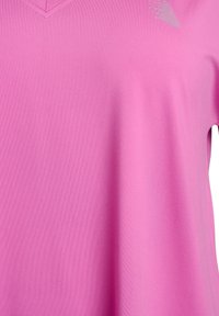 Pink athletic shirt with a V-neck design, made from smooth, lightweight fabric; features subtle reflective accents.
